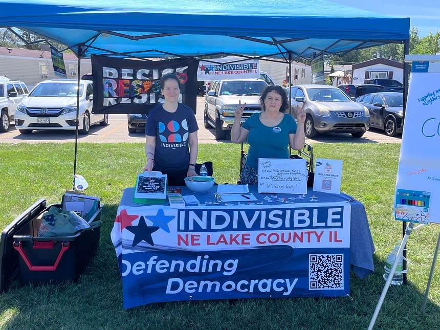Two volunteers at a booth giving out know your rights cards, whistles to the community.